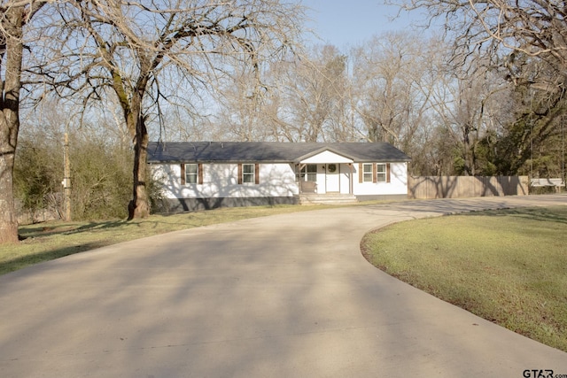 ranch-style house with concrete driveway, a front lawn, and fence