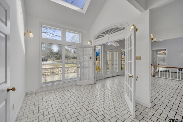 interior space with high vaulted ceiling, french doors, a skylight, and baseboards