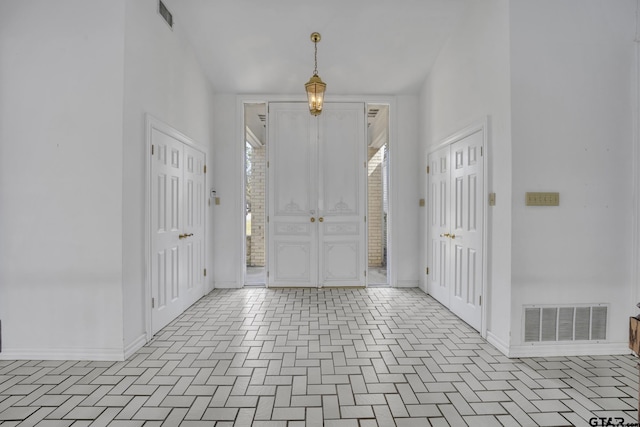 entryway featuring a towering ceiling, baseboards, and visible vents