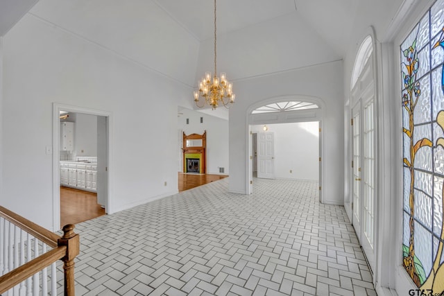 interior space featuring baseboards, high vaulted ceiling, and an inviting chandelier