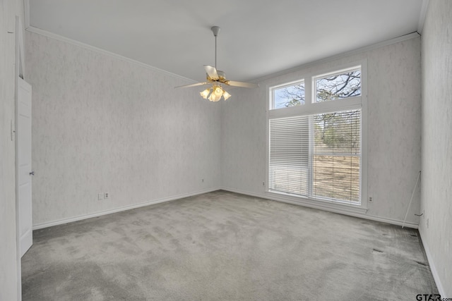 carpeted spare room with crown molding, baseboards, and ceiling fan