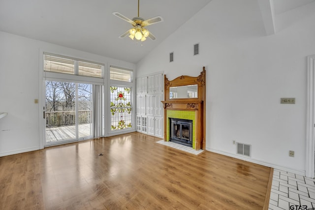 unfurnished living room with high vaulted ceiling, a fireplace, wood finished floors, and visible vents