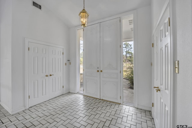 foyer entrance with lofted ceiling, visible vents, and baseboards