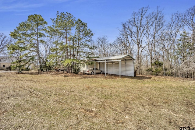 view of yard featuring a detached carport and an outbuilding