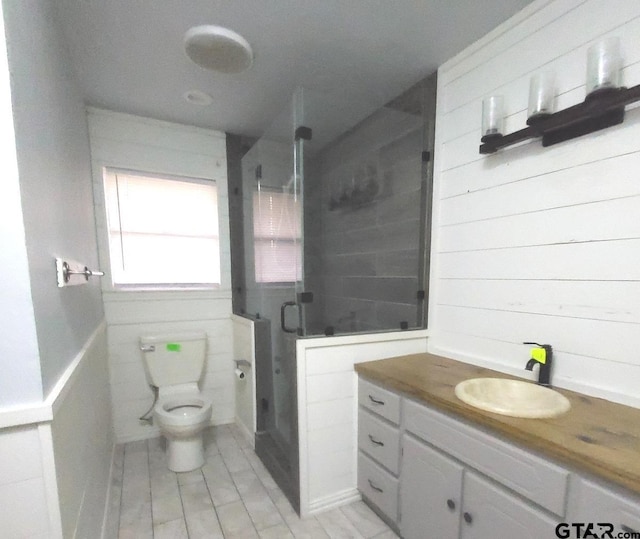 bathroom featuring vanity, a shower with shower door, and toilet