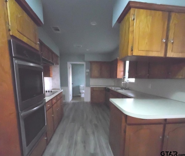 kitchen featuring sink, hardwood / wood-style flooring, double oven, black electric stovetop, and kitchen peninsula