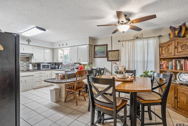 dining room with a textured ceiling, light tile patterned floors, and ceiling fan