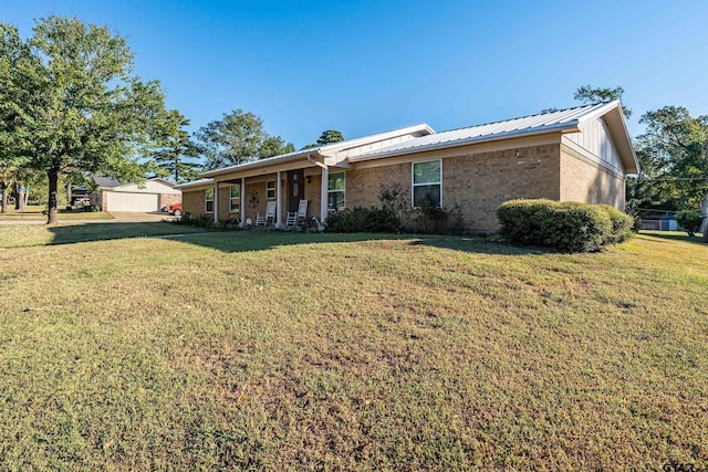 ranch-style home with brick siding, board and batten siding, metal roof, and a front lawn