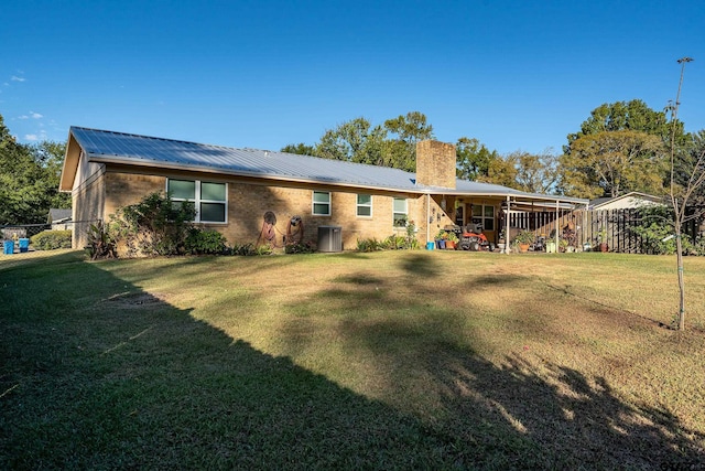 rear view of property featuring a chimney, metal roof, and a yard