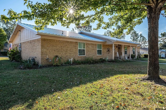 single story home featuring a front yard, brick siding, and metal roof