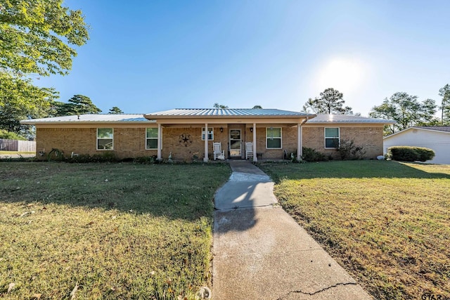 ranch-style house with metal roof, brick siding, covered porch, and a front lawn