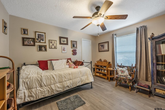 bedroom featuring a textured ceiling, light wood-type flooring, and a ceiling fan