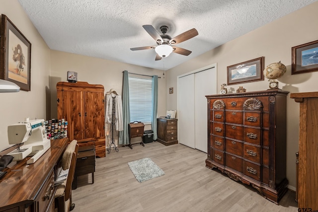 home office with baseboards, light wood-style flooring, a textured ceiling, and ceiling fan