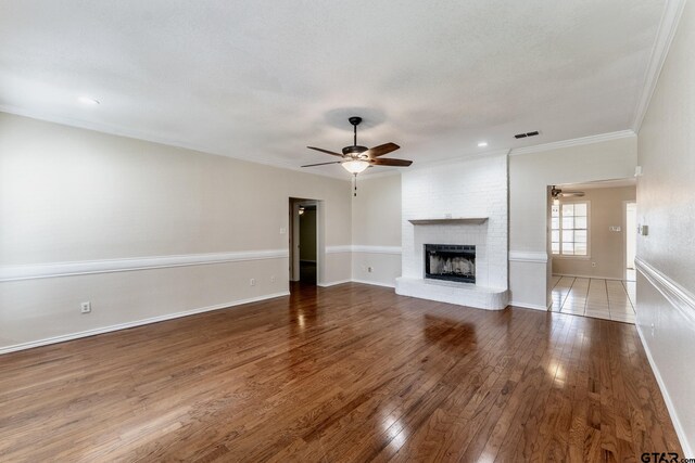 1881 Woodbridge Dr, Sulphur Springs, TX 75482 - unfurnished living room with ceiling fan, wood finished floors, a brick fireplace, ornamental molding, and baseboards