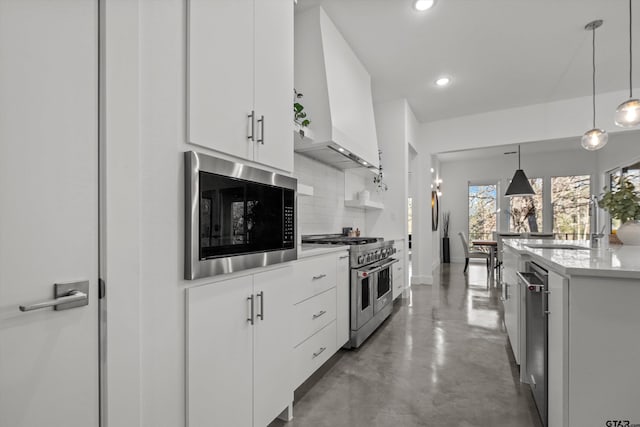 kitchen featuring backsplash, premium range hood, decorative light fixtures, white cabinetry, and stainless steel appliances