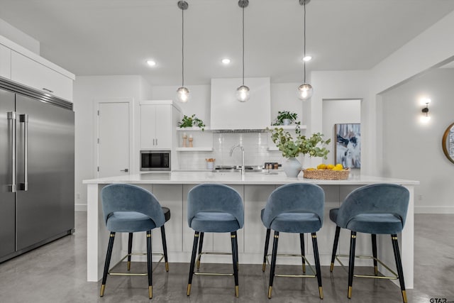 kitchen featuring white cabinets, built in appliances, hanging light fixtures, and a spacious island