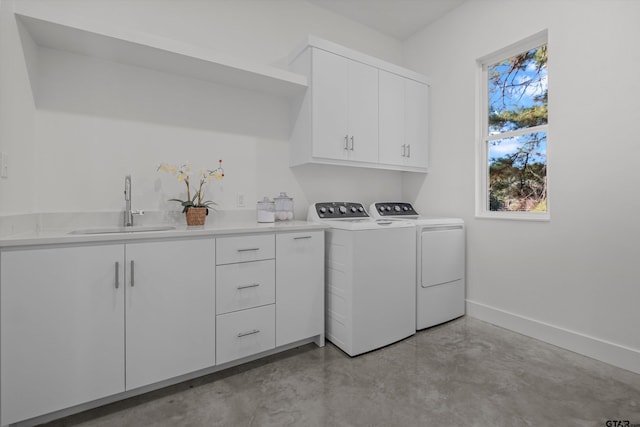 clothes washing area featuring washing machine and dryer, sink, and cabinets