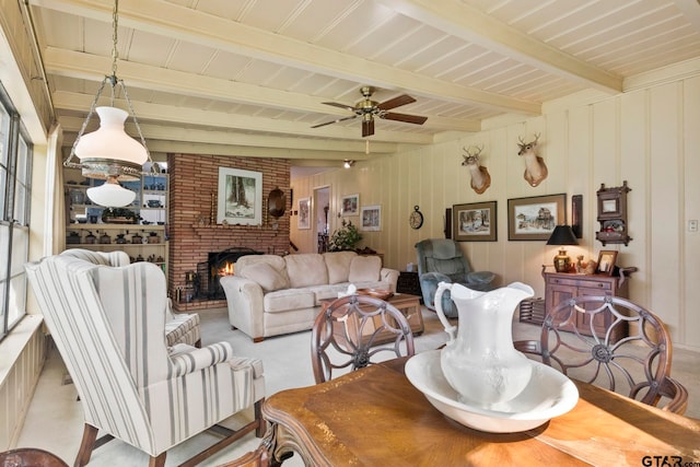 living room with beamed ceiling, ceiling fan, and a fireplace