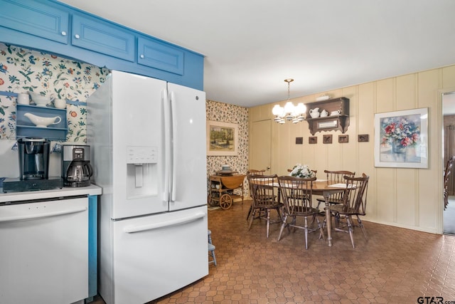 kitchen featuring white appliances, a chandelier, decorative light fixtures, and blue cabinets