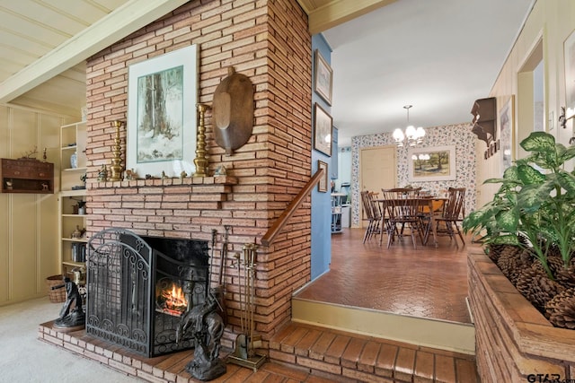 carpeted living room with a fireplace, beamed ceiling, and a chandelier