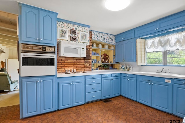 kitchen featuring blue cabinetry, sink, and white appliances