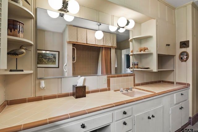 kitchen with white cabinets, tile countertops, sink, and pendant lighting