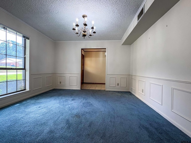spare room with a textured ceiling, a chandelier, crown molding, carpet floors, and a decorative wall
