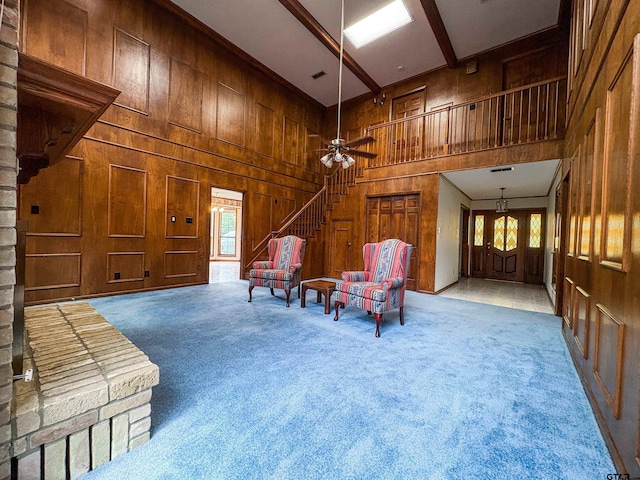 living area with carpet floors, a healthy amount of sunlight, and wooden walls