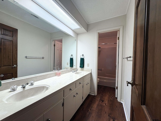 bathroom with toilet, wood finished floors, a sink, and double vanity