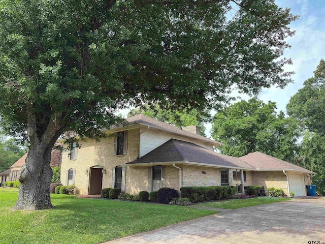 view of front of house with an attached garage, driveway, a front lawn, and a chimney