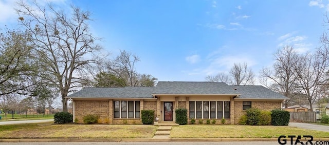 ranch-style house with brick siding, a front yard, and fence