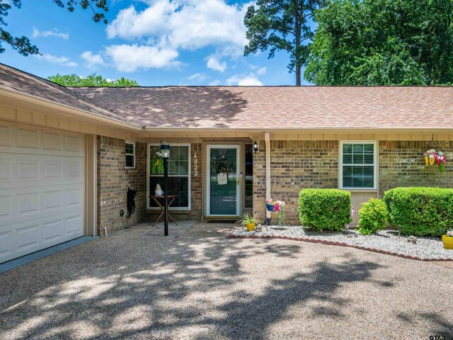 4922 Leaning Oaks Dr, Flint, TX 75762 - view of exterior entry with brick siding, a garage, and a shingled roof