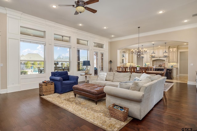 living area with ornamental molding, recessed lighting, dark wood finished floors, and ceiling fan with notable chandelier