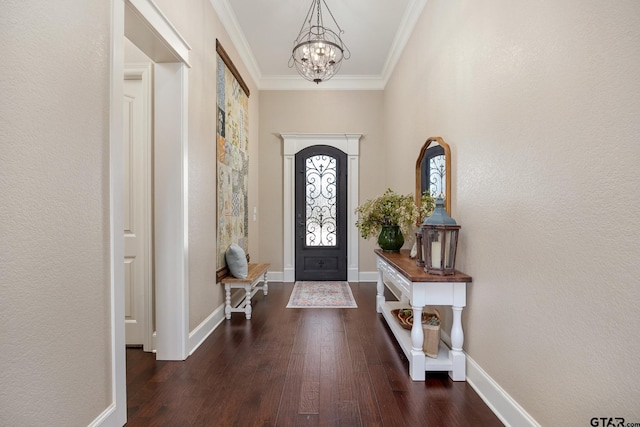 foyer entrance featuring baseboards, dark wood-type flooring, a notable chandelier, and crown molding