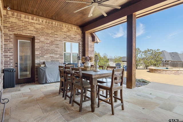 view of patio / terrace featuring a ceiling fan, outdoor dining area, and an in ground hot tub