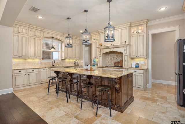 kitchen with cream cabinetry, a breakfast bar, freestanding refrigerator, and baseboards