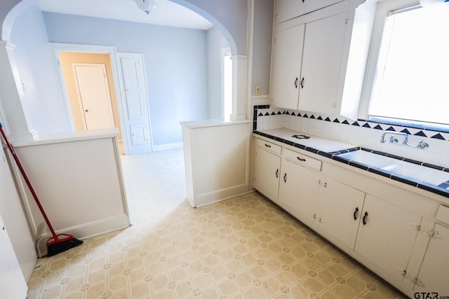 kitchen featuring white cabinetry, sink, tile countertops, and backsplash