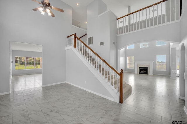 stairs featuring a towering ceiling and ceiling fan