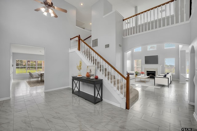 staircase featuring a high ceiling and ceiling fan