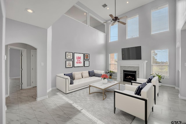 living room featuring a towering ceiling, ceiling fan, and a premium fireplace