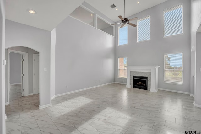 unfurnished living room with a wealth of natural light, a high end fireplace, and a towering ceiling