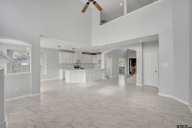 unfurnished living room featuring a towering ceiling and ceiling fan