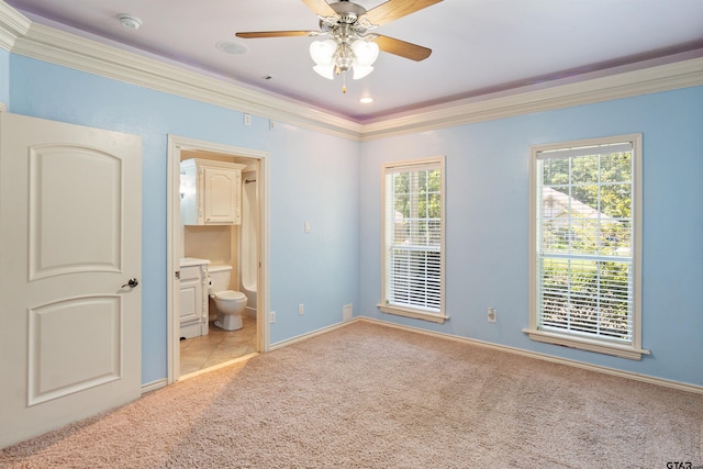 unfurnished bedroom featuring ensuite bath, crown molding, carpet flooring, and baseboards
