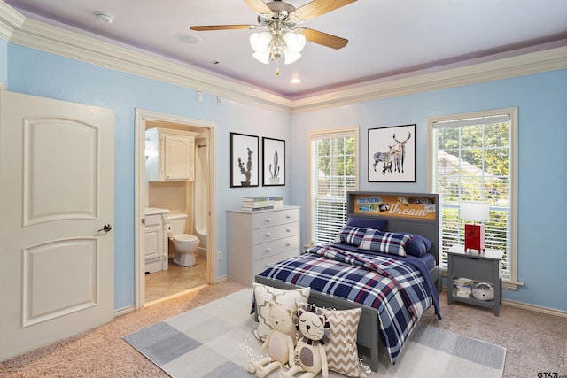 carpeted bedroom with ensuite bath, baseboards, a ceiling fan, and crown molding