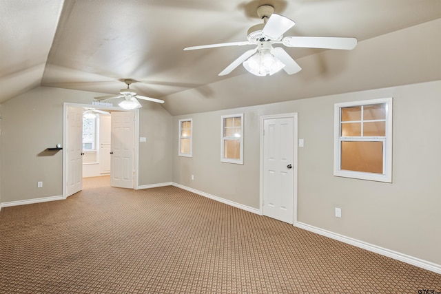 interior space with ceiling fan, vaulted ceiling, light carpet, and baseboards