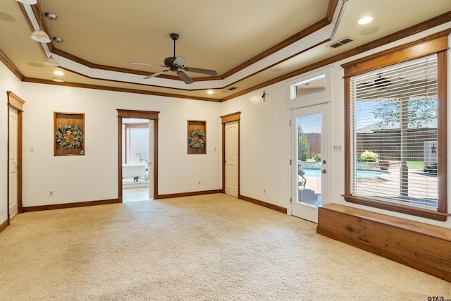 spare room featuring a raised ceiling, visible vents, crown molding, and light colored carpet