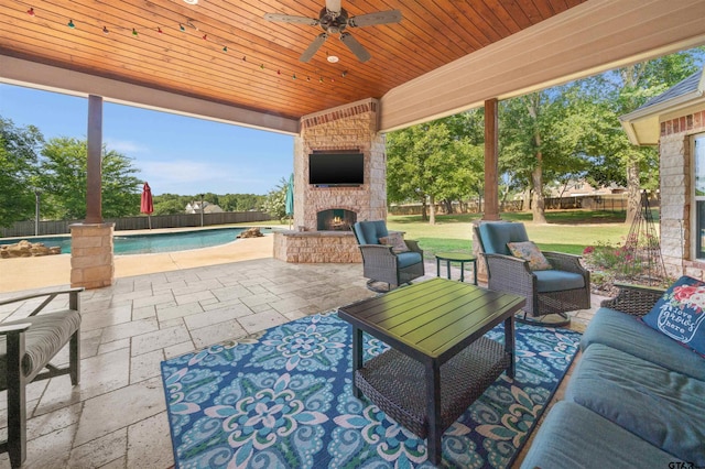 view of patio / terrace with an outdoor living space with a fireplace, ceiling fan, and a fenced in pool