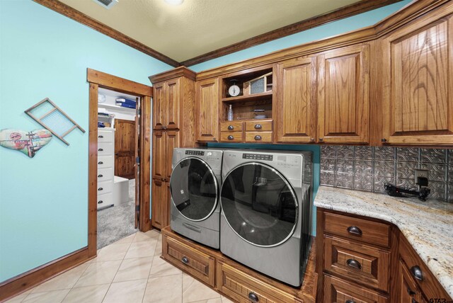 washroom featuring cabinets, crown molding, independent washer and dryer, and light tile patterned flooring