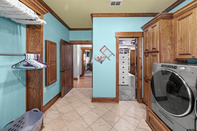 washroom with light tile patterned flooring, cabinets, ornamental molding, and washer / dryer