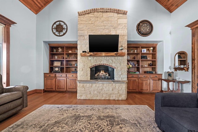 living room with high vaulted ceiling, light wood-type flooring, wooden ceiling, and a fireplace